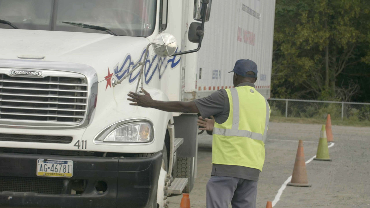Truck driver guided by worker during maneuver