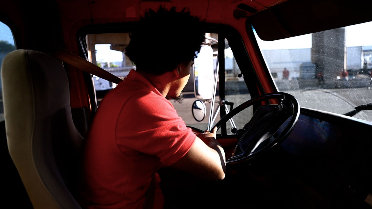 Man driving truck and looking out window at loading dock