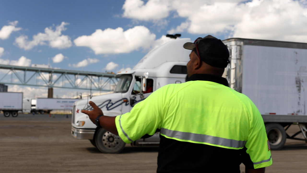 Worker Directs Semi Truck at Industrial Freight Yard