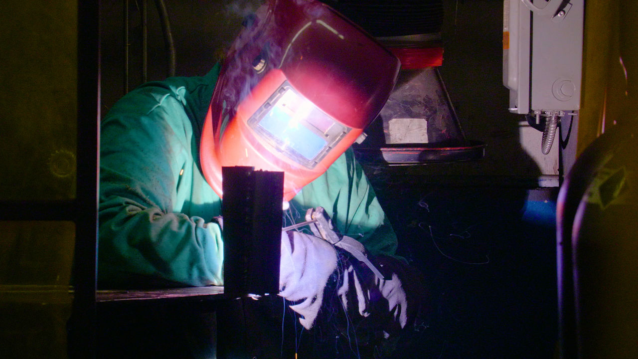 Industrial worker welding metal in workshop setting